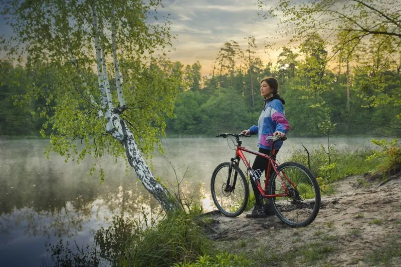 A woman stands with her mountain bike admiring the view