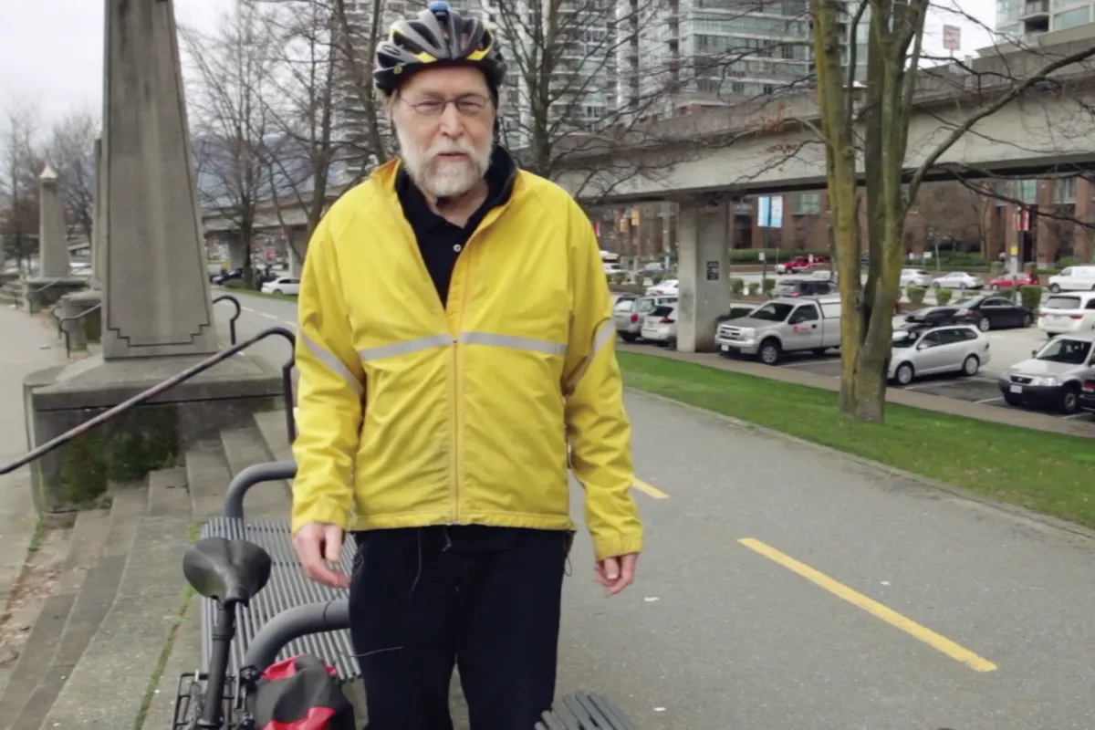 Arno stands in a yellow jacket with his bike.
