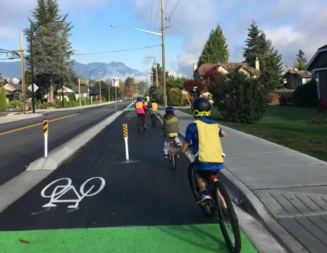 A group of school children ride bikes on the road.