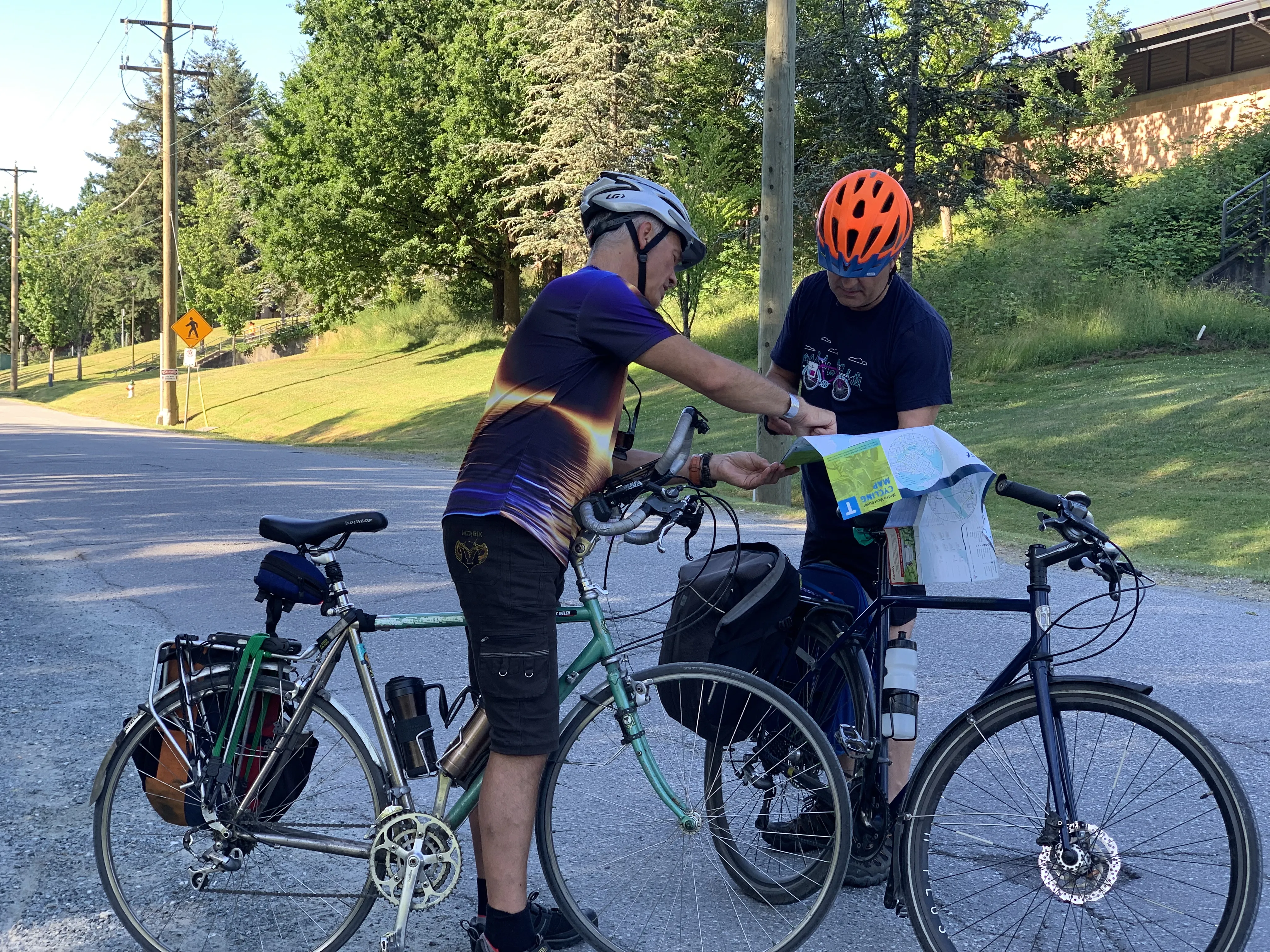 Two men with bikes look at a bike map together.
