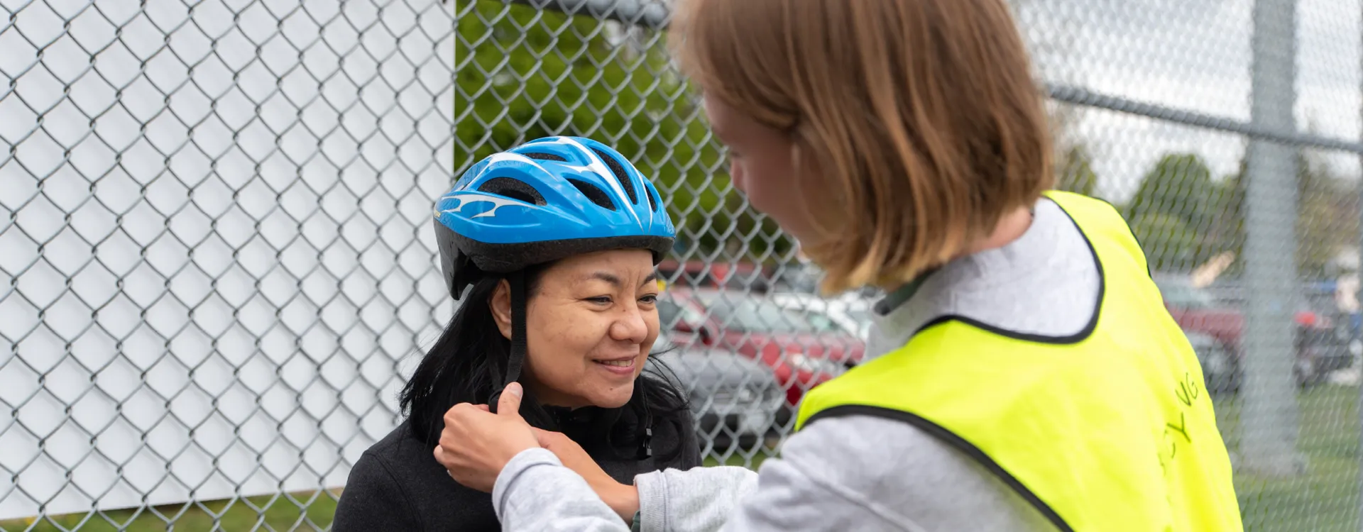 An instructor helps tighten a women's helmet.