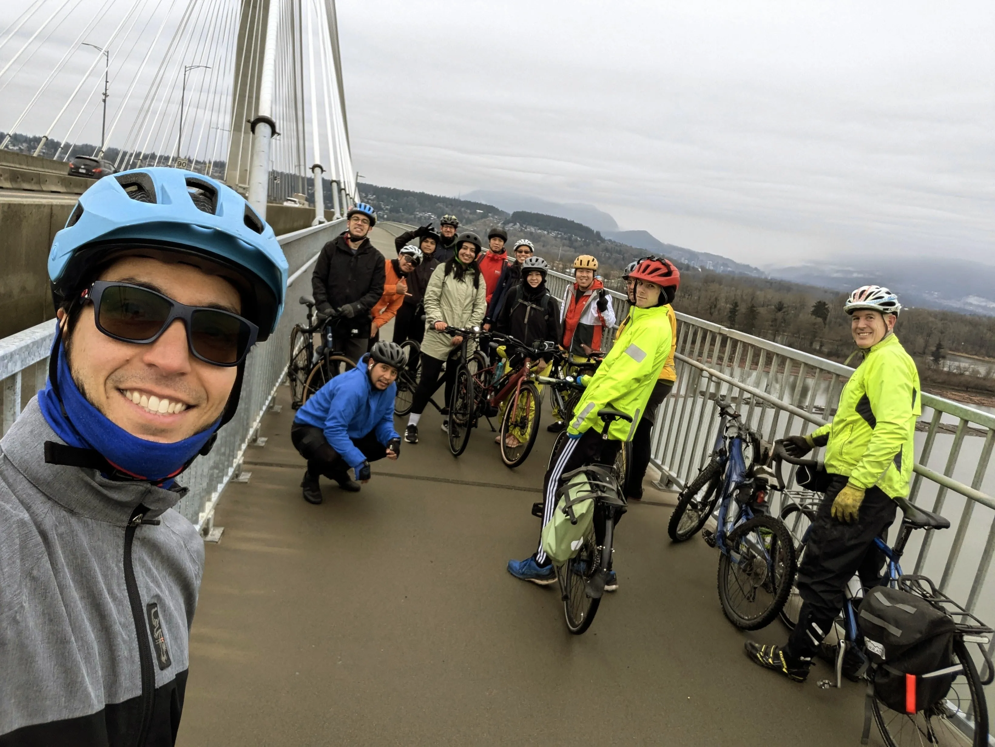 A group of people pose for a photo with their bikes on a bridge.