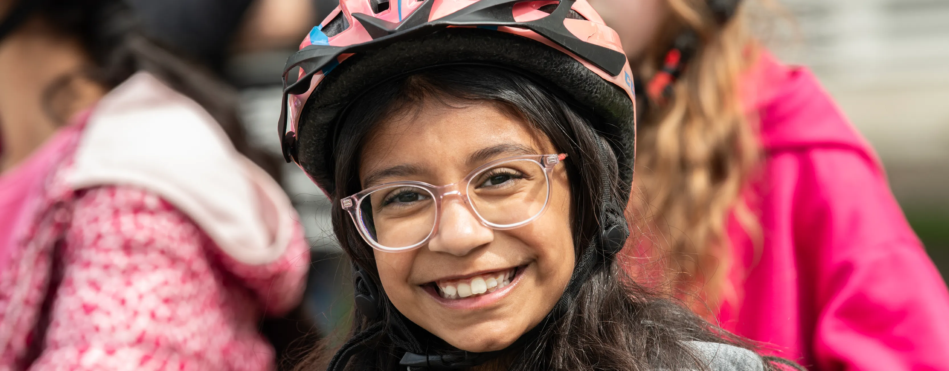 A young school girl wearing a helmet smiles.