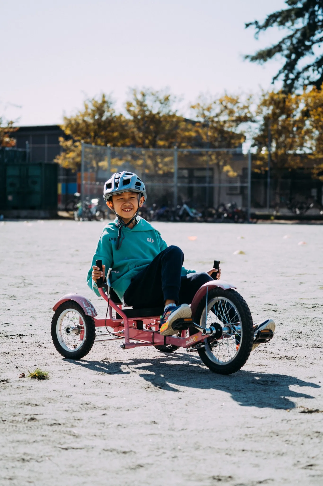 Child wearing a helmet rides a pink three-wheeled 