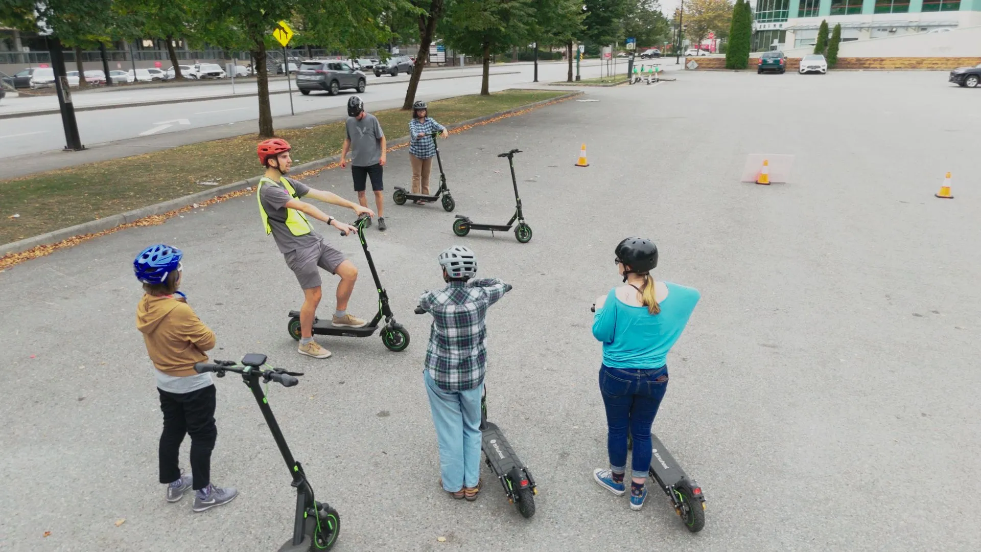 A group of people with e-scooters on a gravel field.