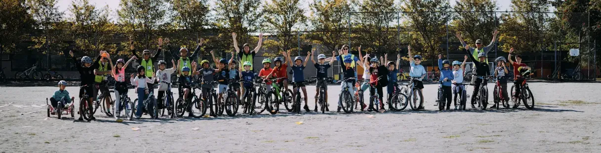 Students and teachers line up with their bikes for a group photo on school grounds.
