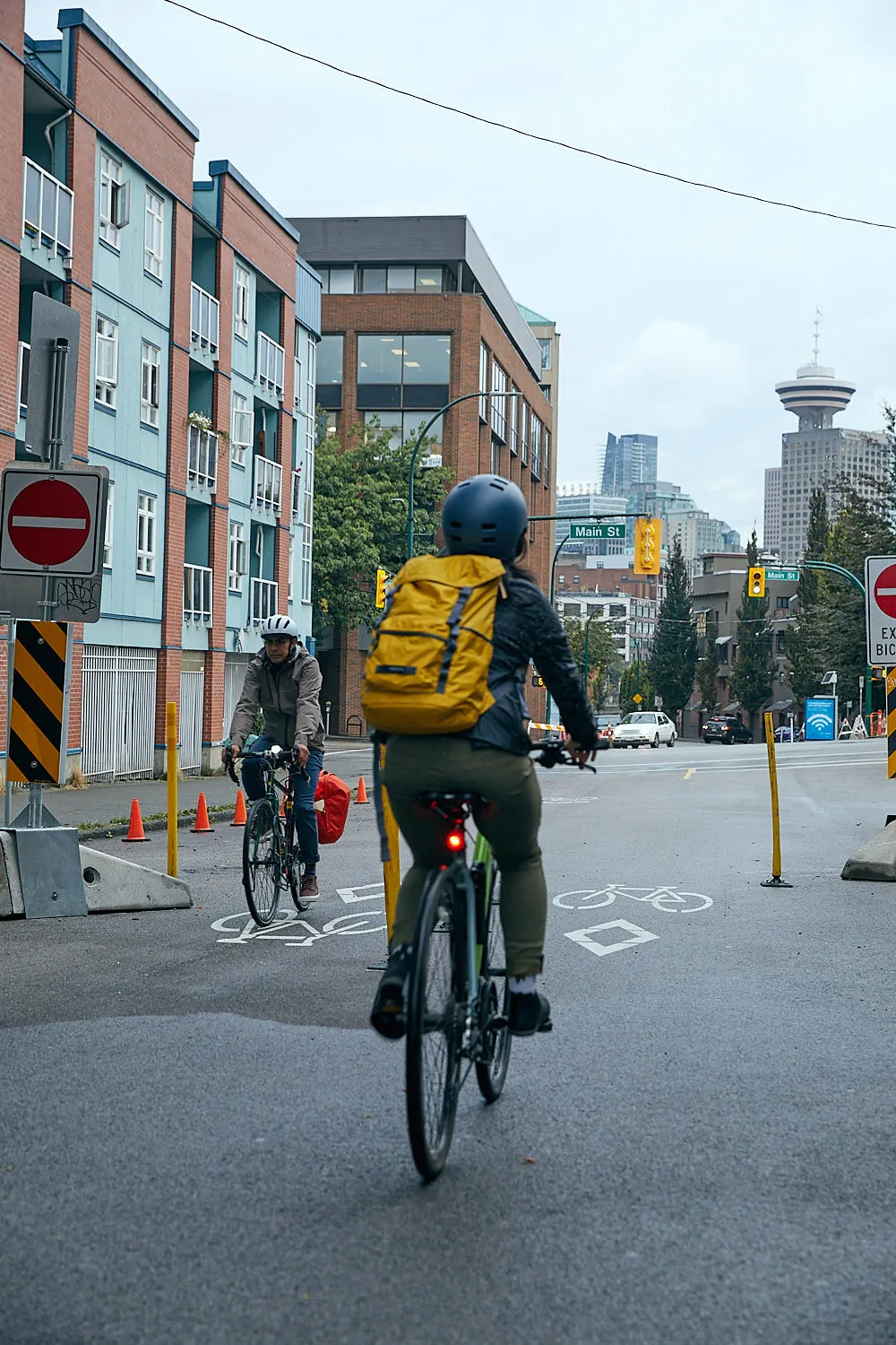 Two people ride their bikes in downtown Vancouver.