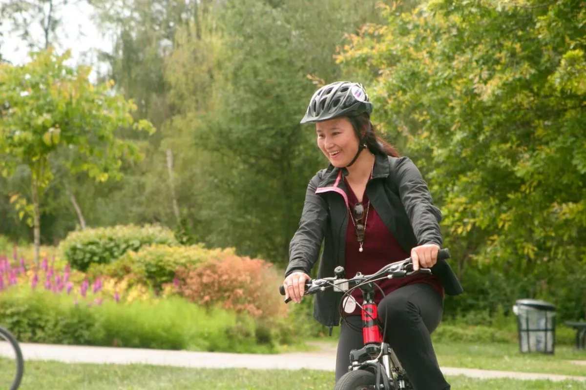 A woman rides her bike in a park.