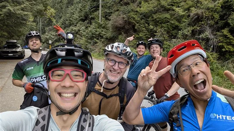 A group of people smile and make silly faces while out for a mountain bike ride.