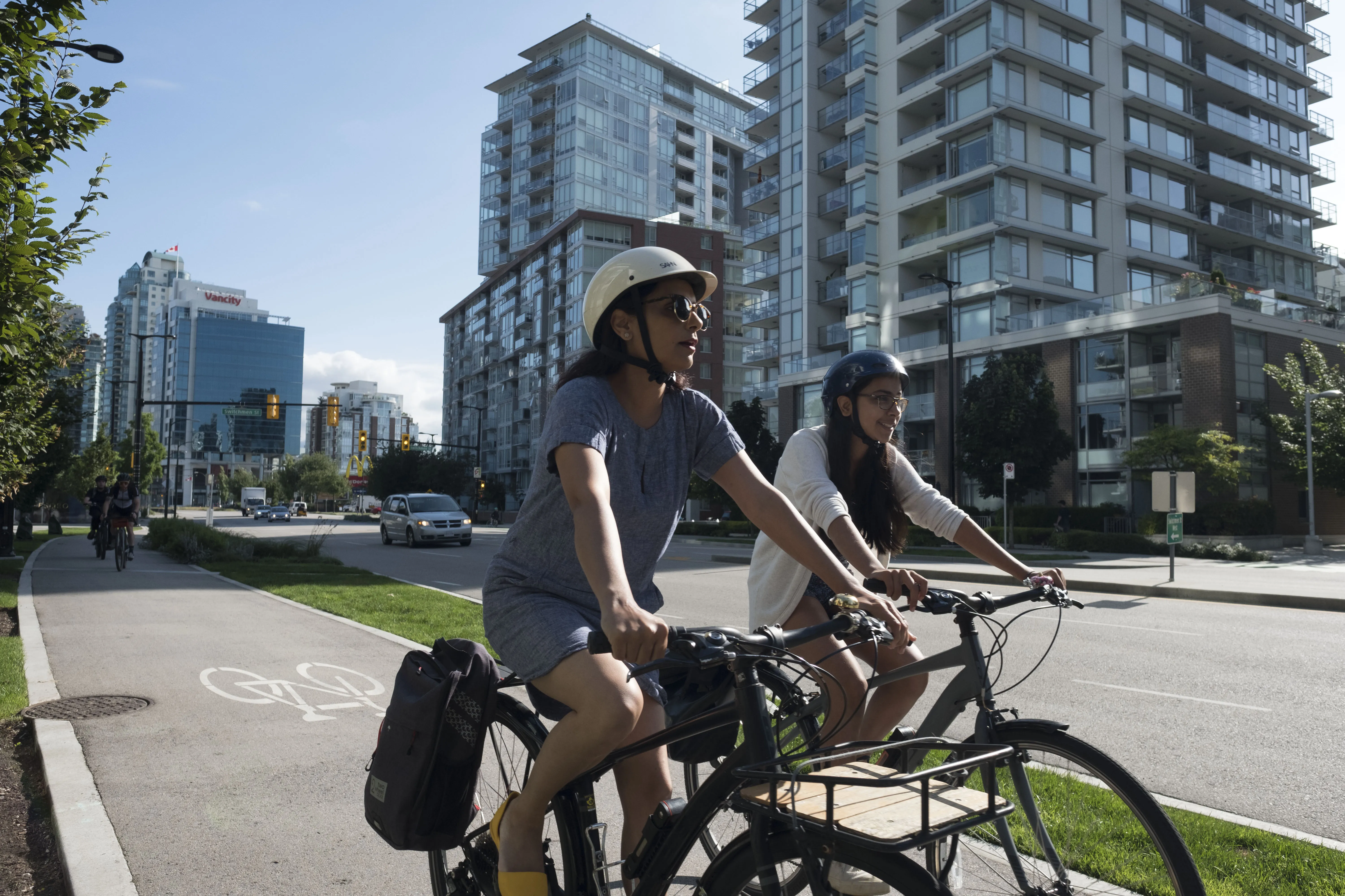 A woman and a girl ride bikes on a bike path.