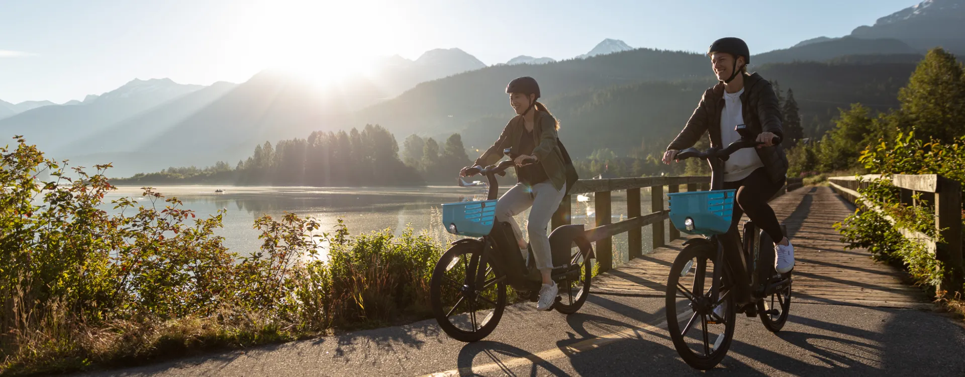 Two young people ride BCAA Evolve e-bikes on a bike path in Whistler.