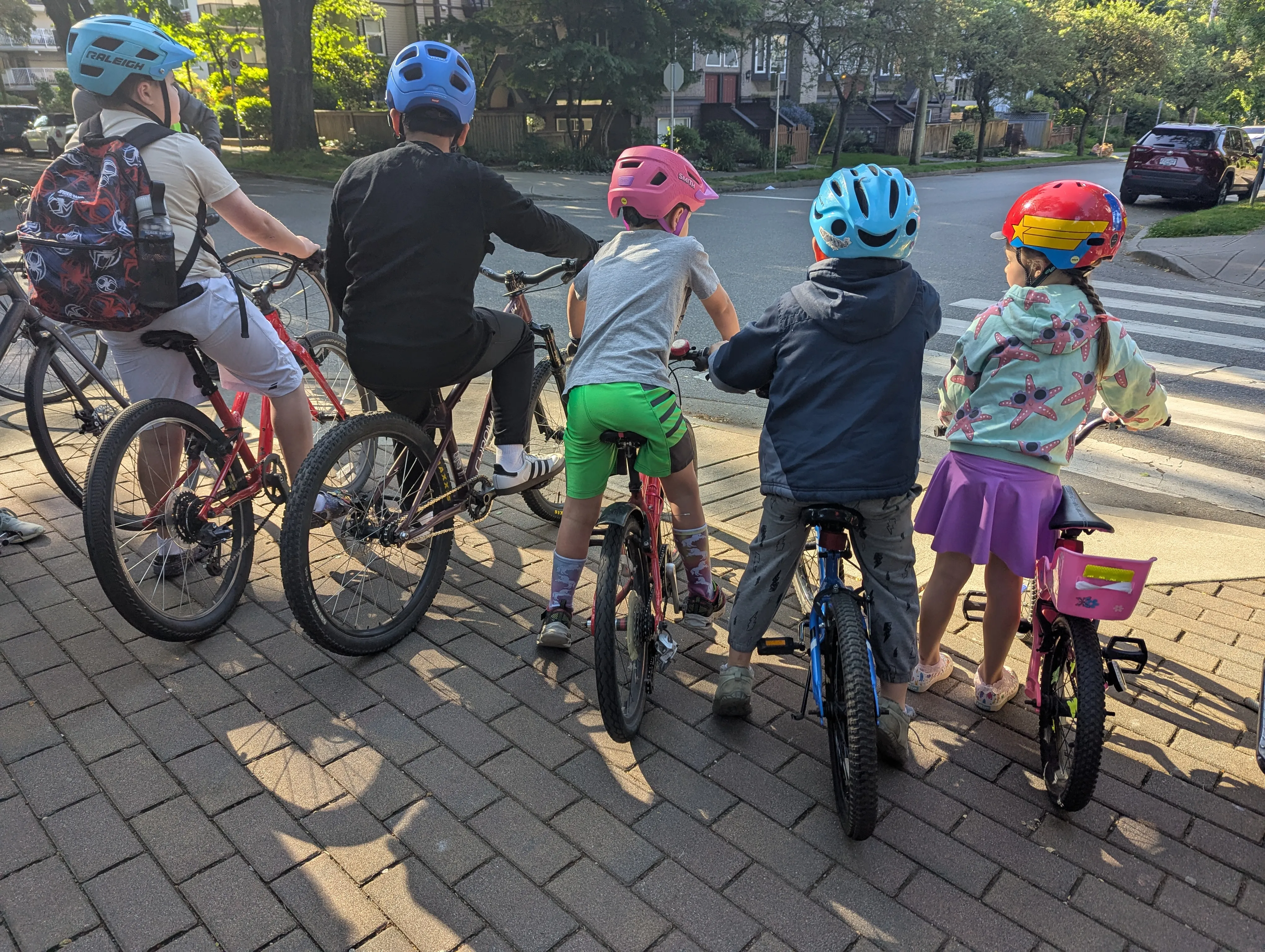 A photo taken from behind as five students with their bikes get ready to ride.
