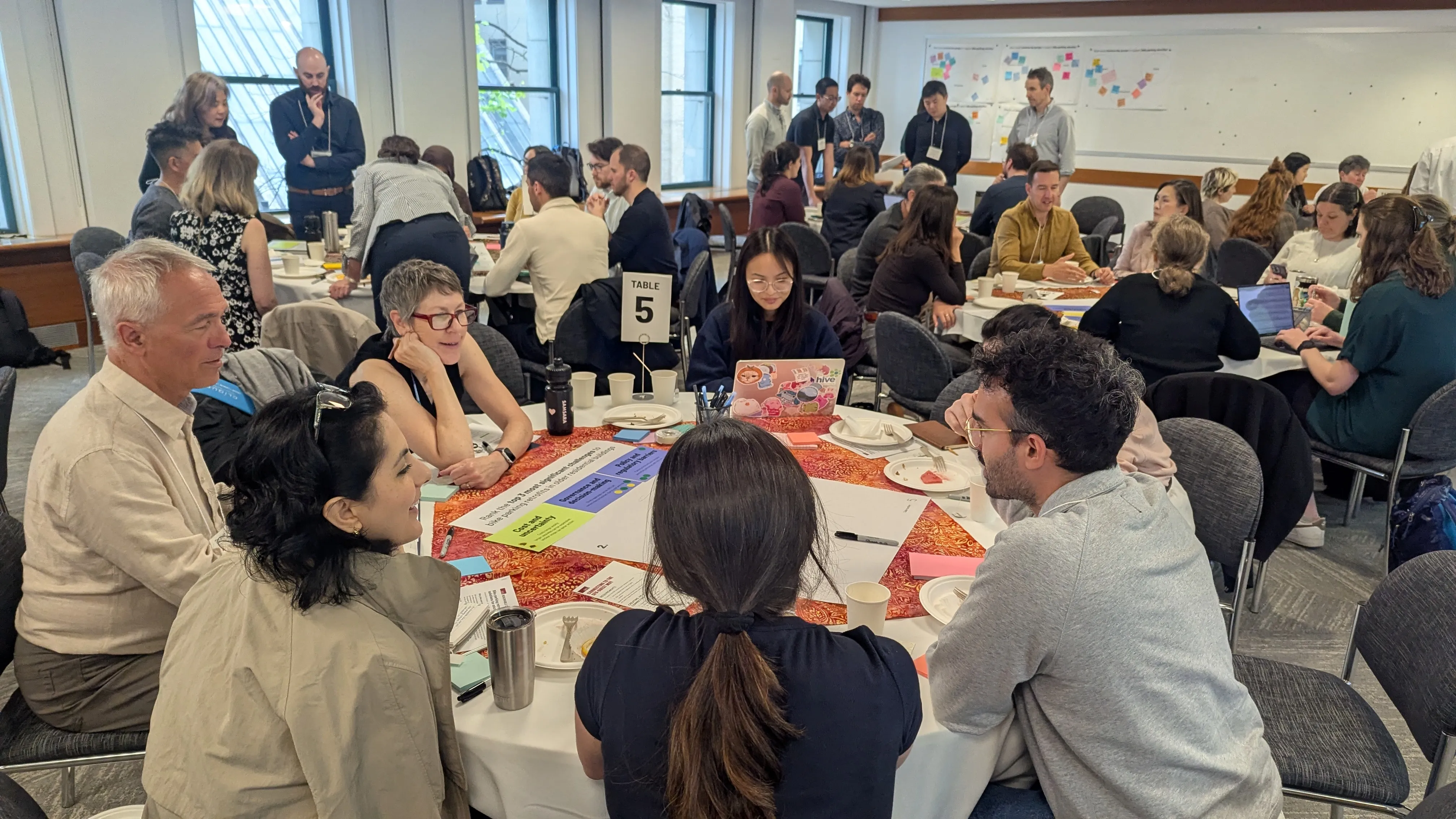 A group of people gather around a table at a bike parking retrofits workshop.