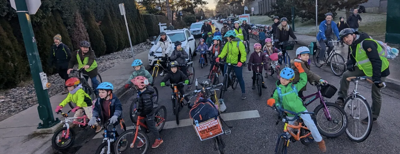 Students, parents, and instructors ride bikes in a bike bus.